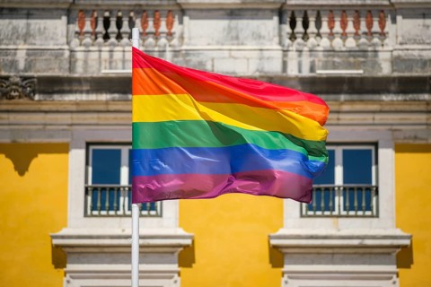 Rainbow pride colors wave on a traditional pride flag in the Lisbon, Portugal sky for LGBT