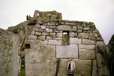Tourists standing in front of huge stone blocks used for Inca masonry, Machu Picchu, Peru, South