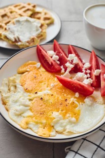 From above a mouth watering setup featuring a plate of fried egg topped with feta cheese,