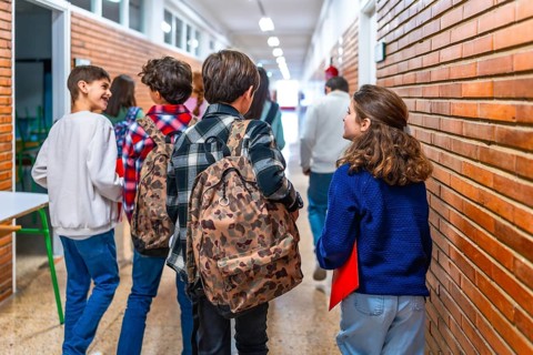 Group of elementary school students walking in the hallway between classes, chatting and carrying