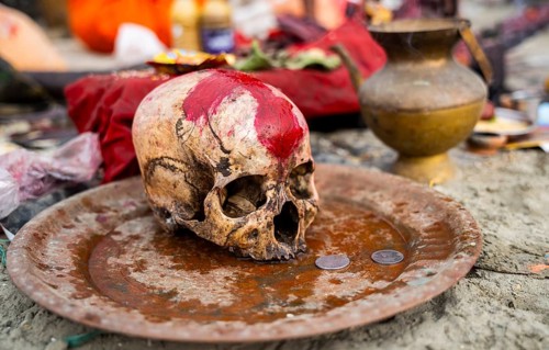People offer coins to a human skull as they offer prayers on the bank of Brahmaputra river on