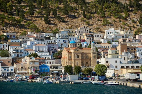 Port town with lively shore, buildings and a distinctive waterfront church, Pothia, main town,
