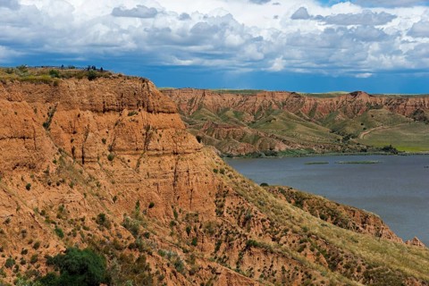 Ein felsiger Canyon, der sich an einem See mit dichtem grauen Himmel darüber erstreckt, Barrancas