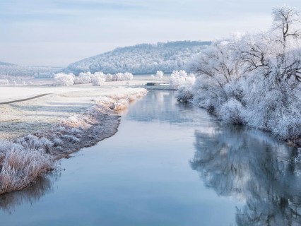 The river Unstrut in the Unstrut valley in winter, fields, trees and forests covered with