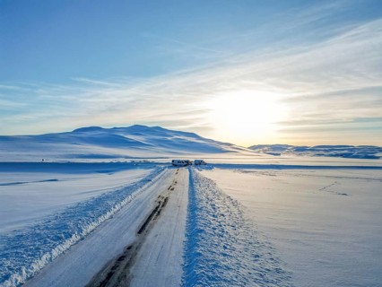 Aerial drone view. Frozen road in winter in Iceland. Snow-filled roadsides during winter with blue