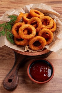 Deep fried onion rings, appetizer, with tomato sauce, on a wooden table, no people, favorite dish