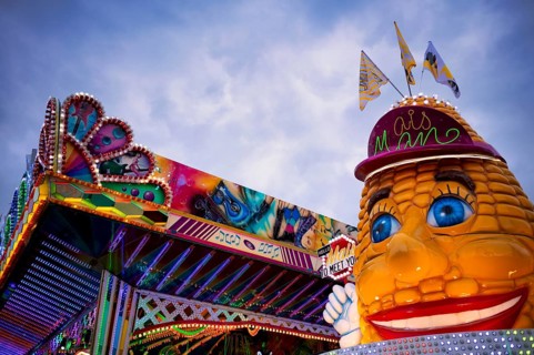 Fairground ride and food stand corn on the corn cob, neon light, carnival, spring festival, folk