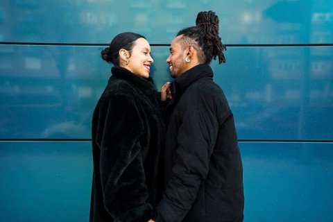 A multiethnic couple standing closely, sharing a tender moment. They express love and cultural