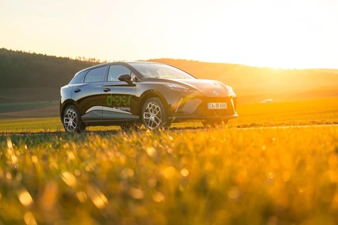 Black car on a road with a view of fields and sunset, e-car sharing vehicle from Deer Mobility,