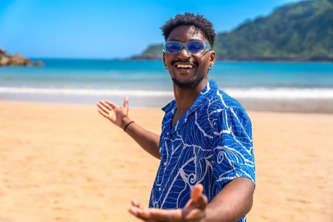 Young black man with sunglasses and hawaiian shirt enjoying summer holidays welcoming people to a