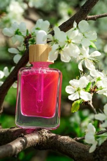 Pink oil or serum for face or hair with natural flower extract, presented in a clear glass bottle