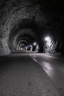 Interior view of an illuminated tunnel with rock faces and asphalt road, Zillertal, Austria,