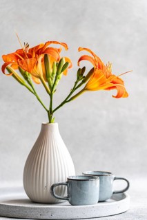 Vibrant orange tiger lilies elegantly arranged in a white vase, placed on a minimalist circular