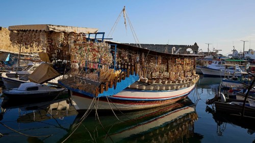 Boat in harbour loaded with souvenirs, reflected in calm water, harbour area, Rhodes Town, Rhodes,