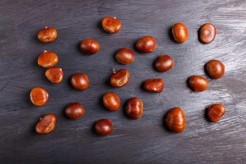 Pile of sweet chestnuts on black wooden background with copy space, top view