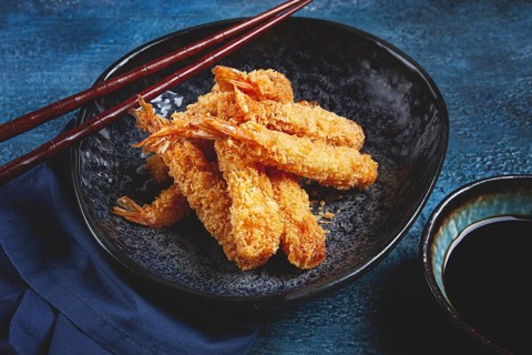 Shrimp in tempura, deep fried, on a black plate, with soy sauce, close-up, top view, no people