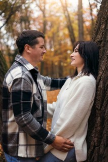 A couple shares a heartfelt moment in a vibrant autumn forest, surrounded by colorful leaves and