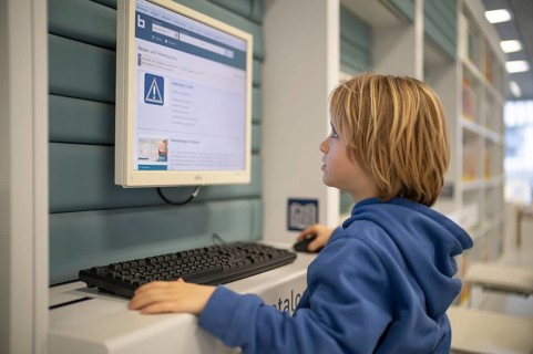 Interior shot, boy, 6 years old, blonde, operating computer, PC station, city library catalog,