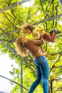 Vertical photo of a caucasuan blonde mother lifting playful girl standing on a park