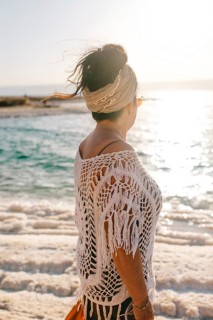 Side view of unrecognizable woman with a headscarf gazing towards the sunlit horizon over Dead Sea
