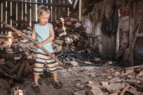 Little boy working in a shed with pitchfork