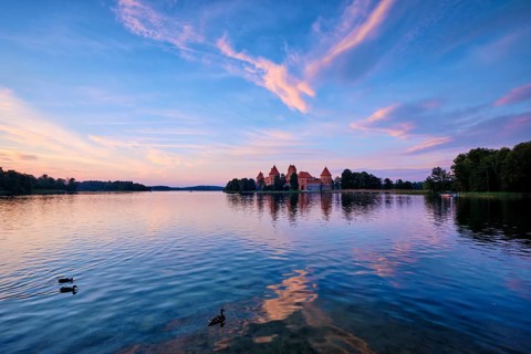 Trakai Island Castle in lake Galve, Lithuania on sunset with dramatic sky reflecting in water and