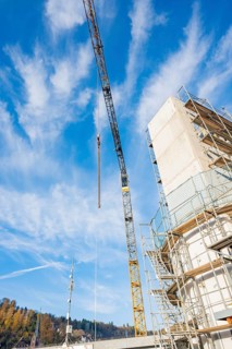 Crane towers over a construction site with stair scaffolding, clear blue sky and natural