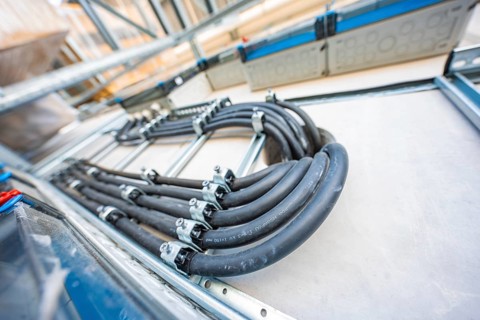 Black cables are mounted in a metallic structure in an electrical system, electrical system for PV
