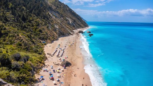Drone shot of beautiful crystal clear turquoise and blue water at Megali Petra sandy beach in