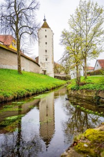 Clear moat reflecting an old tower surrounded by spring greenery, Isny, Allgäu, Bavaria, Germany