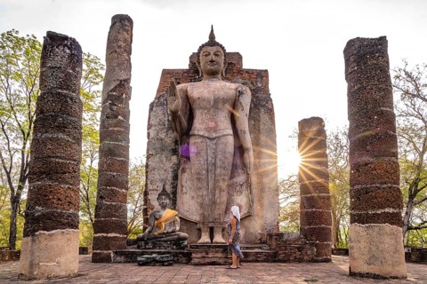 Tourist in front of the giant standing Buddha in the temple Wat Saphan Hin, UNESCO World Heritage