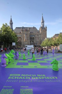 Chess game and playground at the Gothic town hall with square granus tower and round market tower,