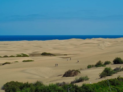 People walk through the vast sand dunes with views of the sea, Maspalomas Dunes, Gran Canaria,