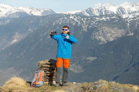 A man enjoys a trek in the Pyrenees, capturing a selfie amidst the stunning mountain backdrop.