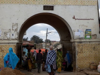 Harar city gate, market scene with people wearing traditional clothes under an archway, Harar,