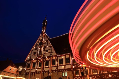 Advent calendar at the town hall, rotating carousel in the foreground, Christmas market in