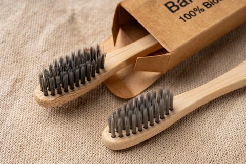 From above view of bamboo toothbrushes on a textured burlap background, showcasing eco-friendly