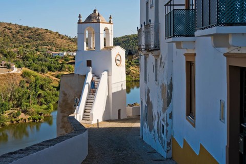 A woman in a blue summer dress climbs the clock tower (Torre do Relogio), which was built in one of