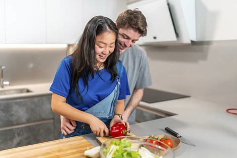 Asian woman and caucasian man enjoying a cooking session at home, showcasing everyday life and
