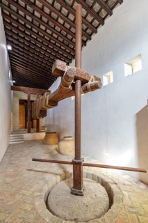 Antique wine press with solid wooden beams on a stone floor in a simple room, Jerez