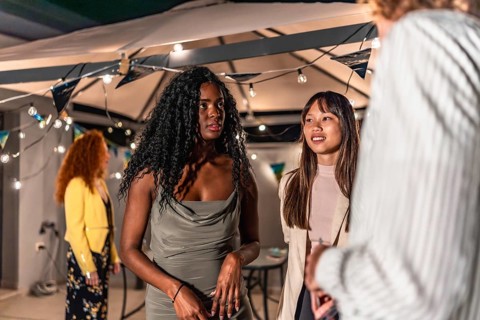 Multi-ethnic fiends dressing elegant clothes chatting calm during night party at terrace