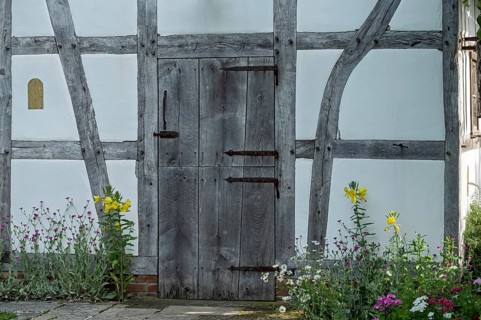 Wooden door of a half-timbered house surrounded by blooming flowers in rustic style, Germany