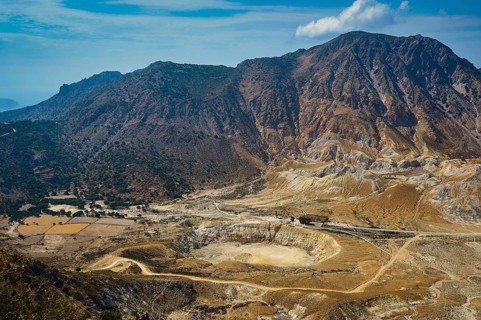 Geological formations and sparse vegetation in an impressive volcanic landscape with majestic