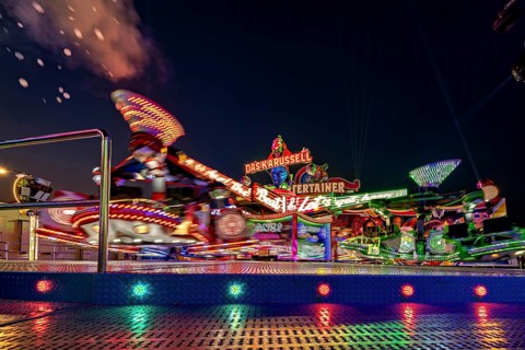Glowing carousel in the lively atmosphere of a night-time fair, carousel and hustle and bustle of