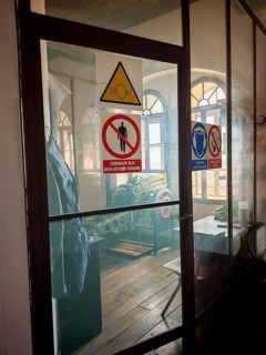 An industrial interior in the Lotrscak Tower with cannon and warning signs behind a glass door,