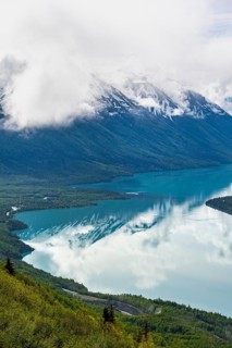 View of snowy mountains in spring and turquoise Kenai Lake with reflection, Slaughter Ridge Trail,