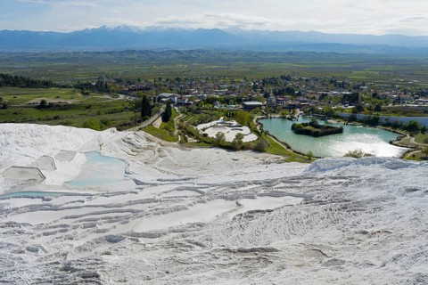 View of travertine terraces with adjacent urban landscape and mountain scenery, sinter terraces,