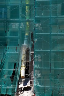 Construction site, house with scaffolding and a net in front of it as dust protection, waste tunnel