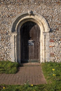 Chevron mouldings around doorway with weathered carved faces, Wantisden church, Suffolk, England,