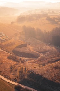 Aerial view of a landscape with fields and hills in warm autumn colors at sunset, Earth landfill,
